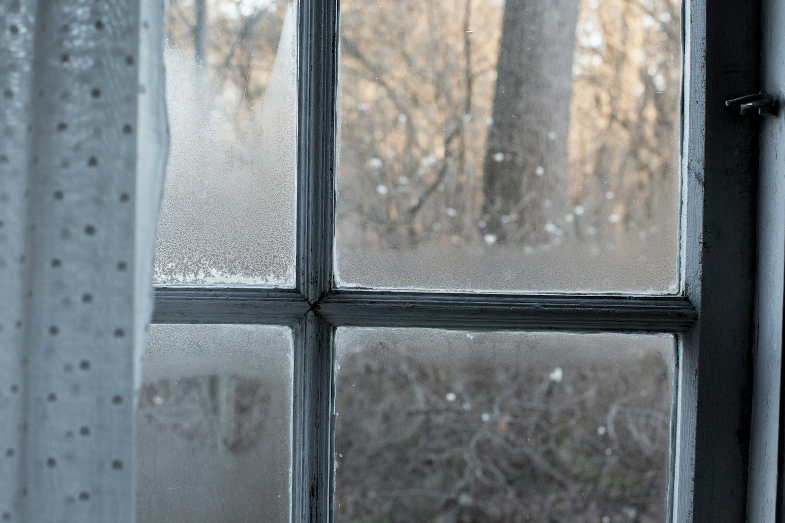 Fensterscheibe mit Kondenswasser in einer Altbauwohnung im Winter