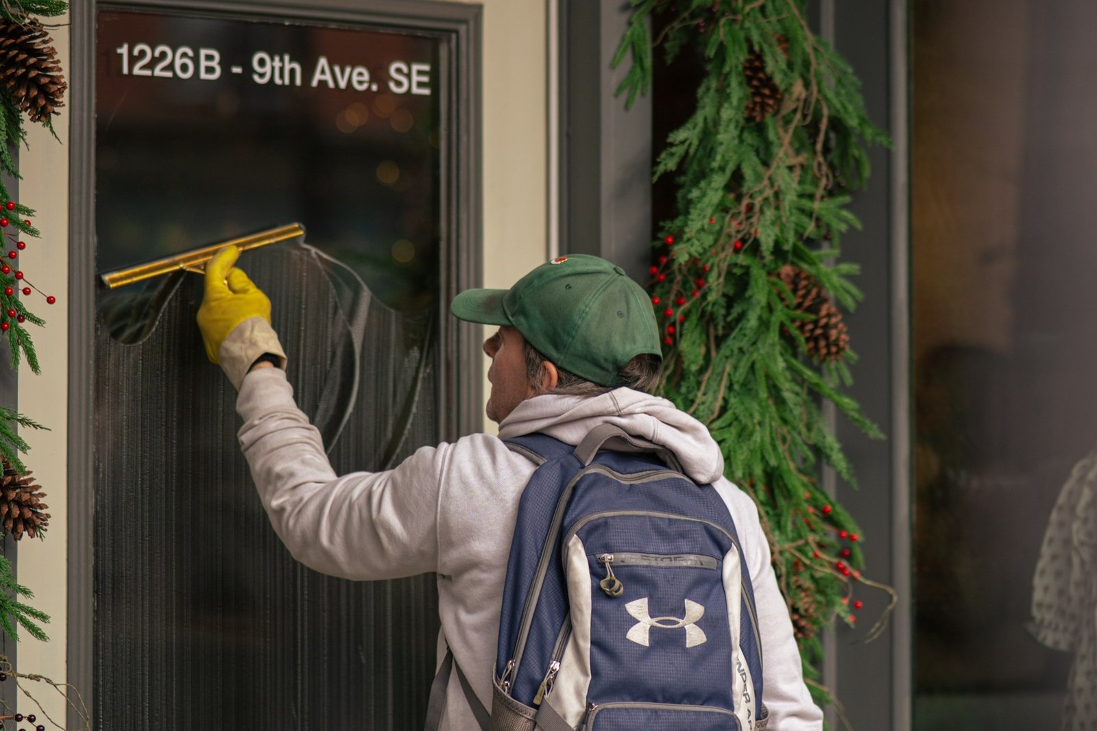 Hand hält einen Fensterabzieher auf einer nassen Fensterscheibe